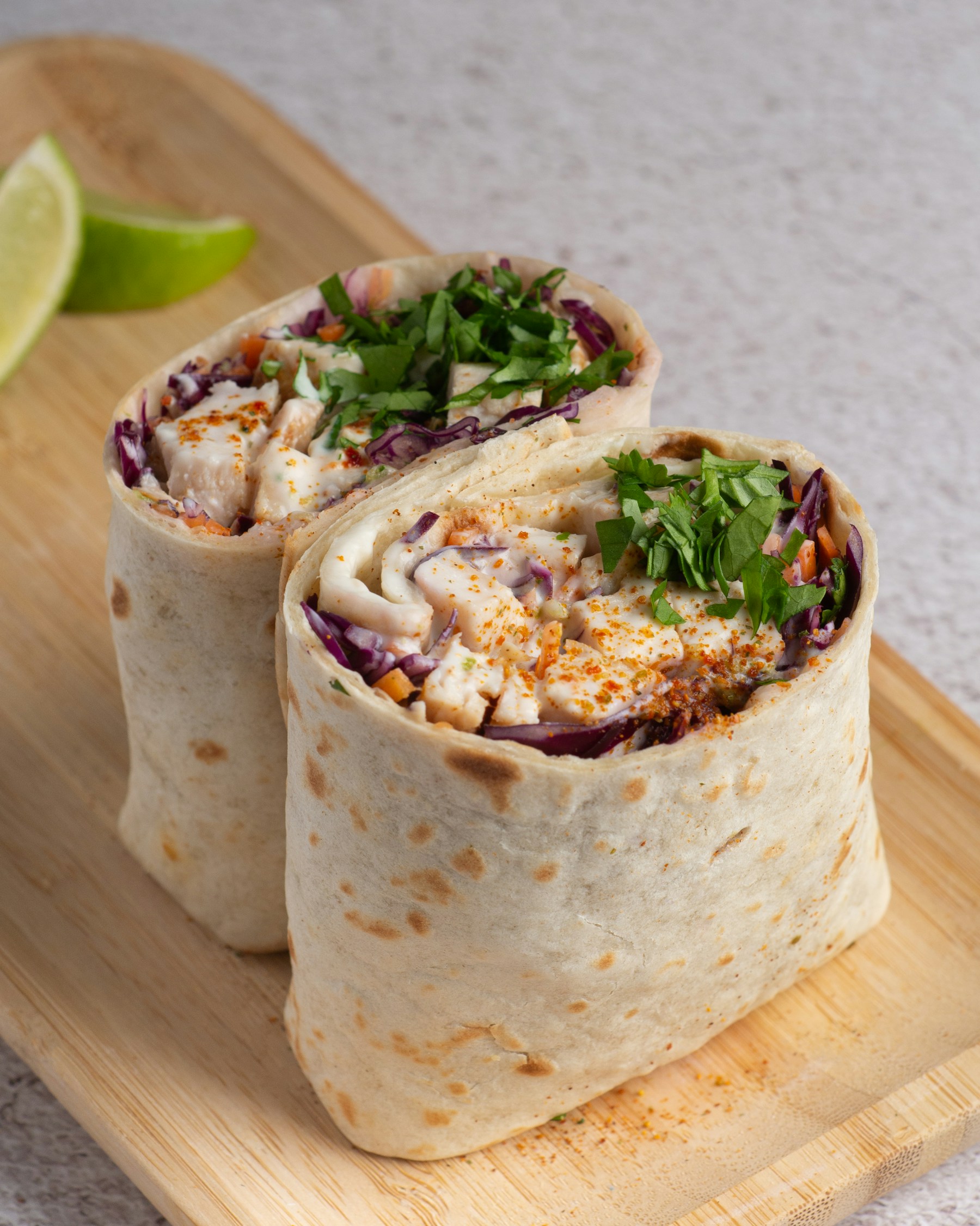 Two freshly prepared burritos filled with chicken, vegetables and herbs